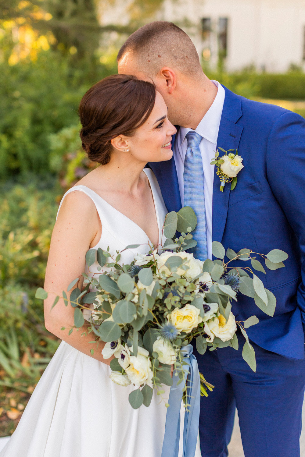 Groom in a blue suite hugging her bride