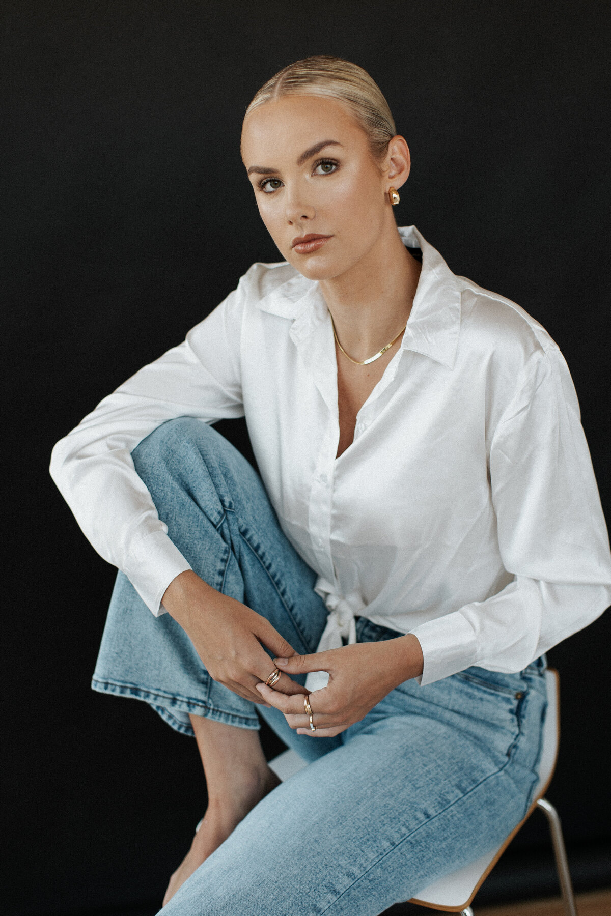 Professional portrait of a girl with a slick-back bun shot against a black backdrop for a salon branding session.