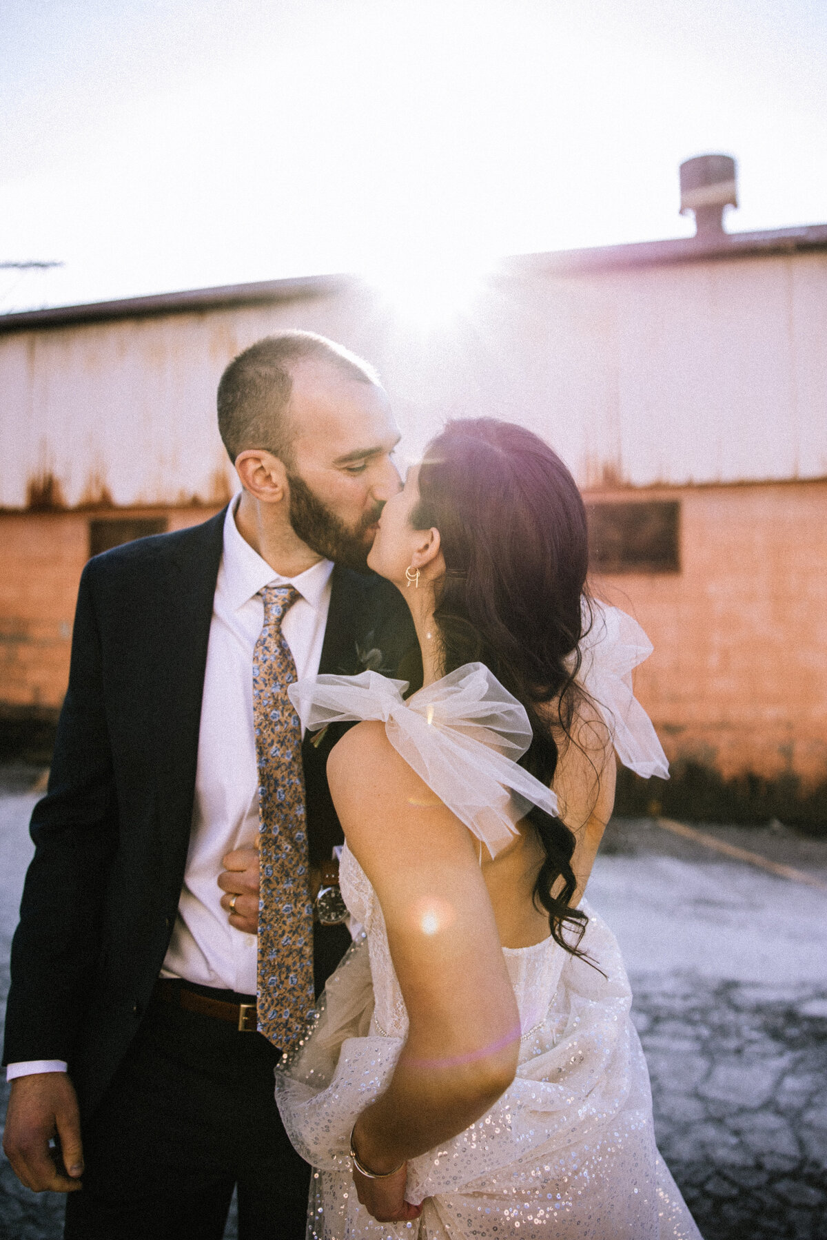 Bride and groom kissing in the sunlight in an alley by Franklin on Penn. 