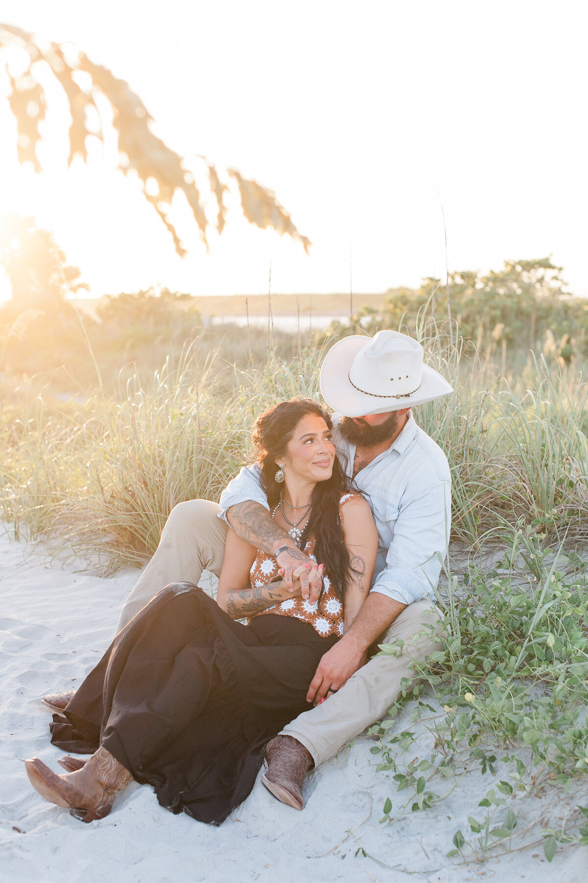 Mom and dad cuddling in the dunes at sunset