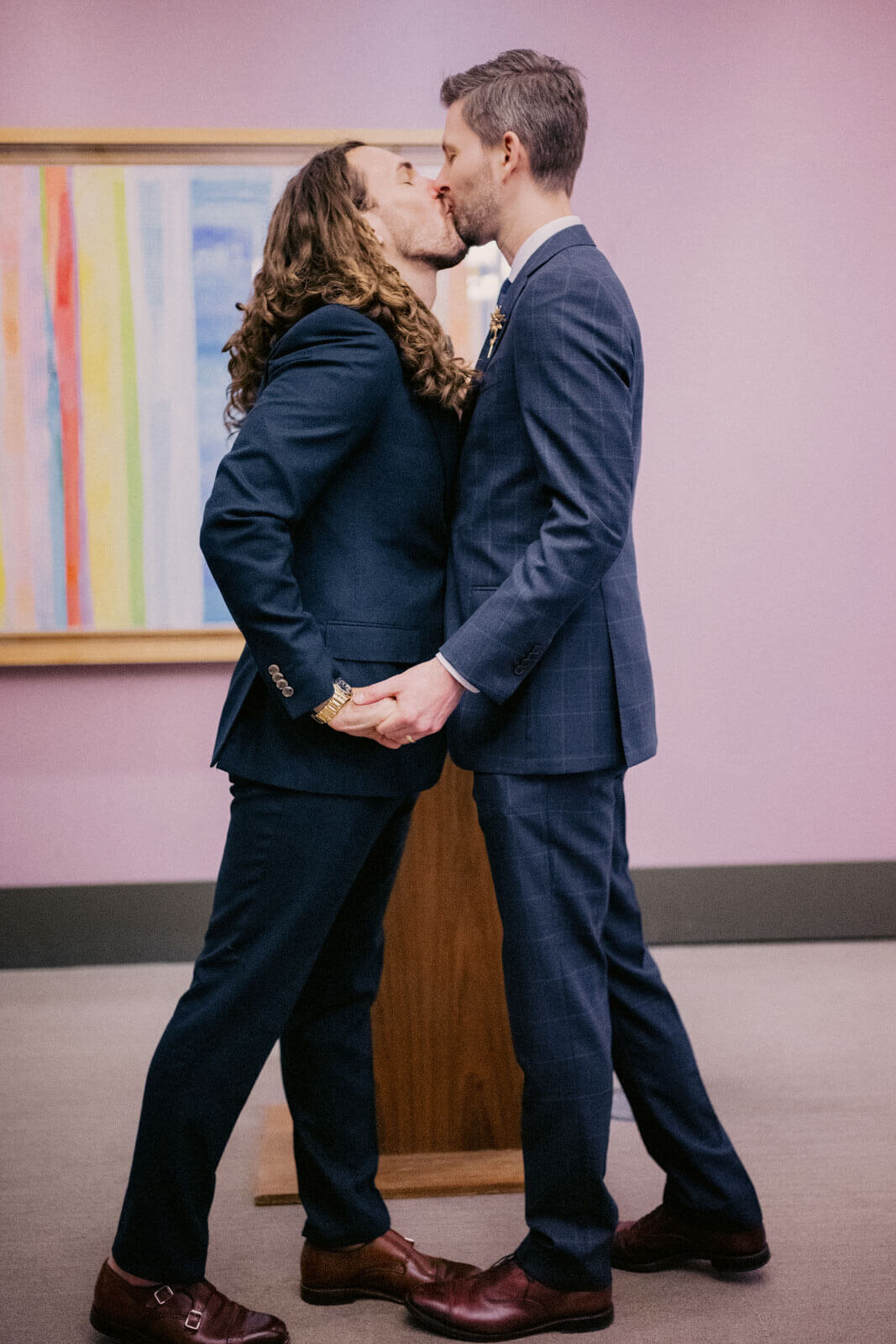 The two grooms kiss each other while holding hands during the ceremony. NYC City Hall Elopement Image by Jenny Fu Studio