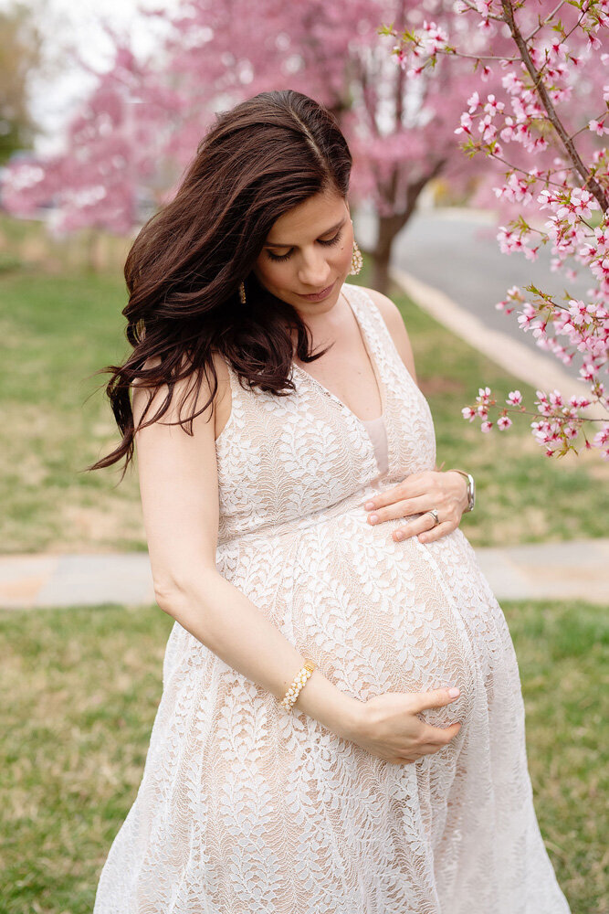 Maternity session of woman standing under cherry blossoms