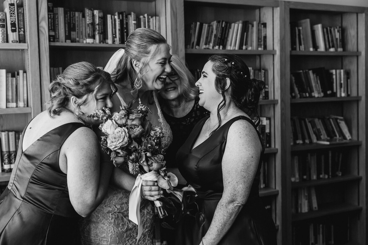 Bride and bridesmaids share a joyful laugh together in a library just before the ceremony at a Jacksonville wedding.