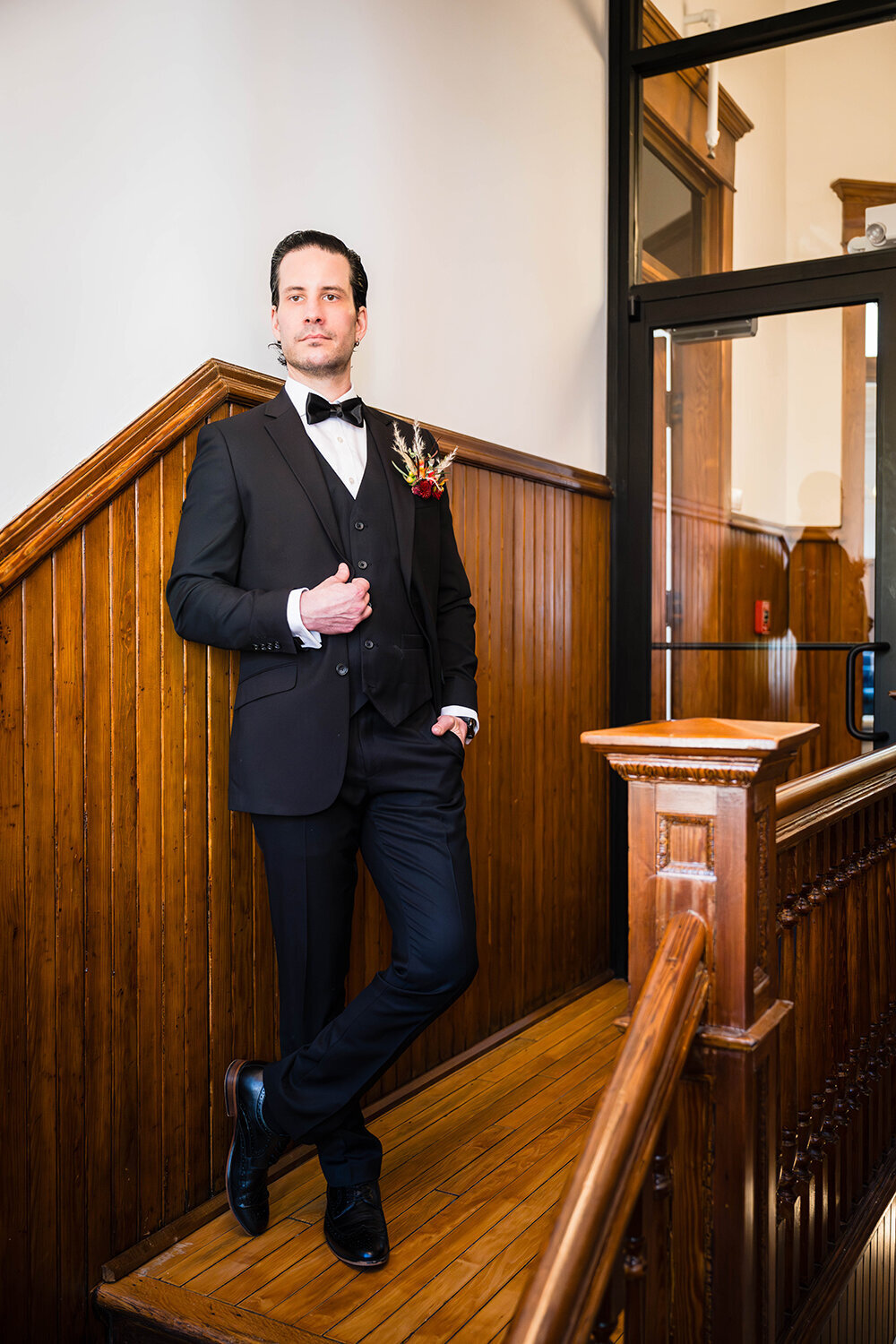A groom stands at the top of a stairwell in a hotel in Roanoke, Virginia for formal portraits on his elopement day.