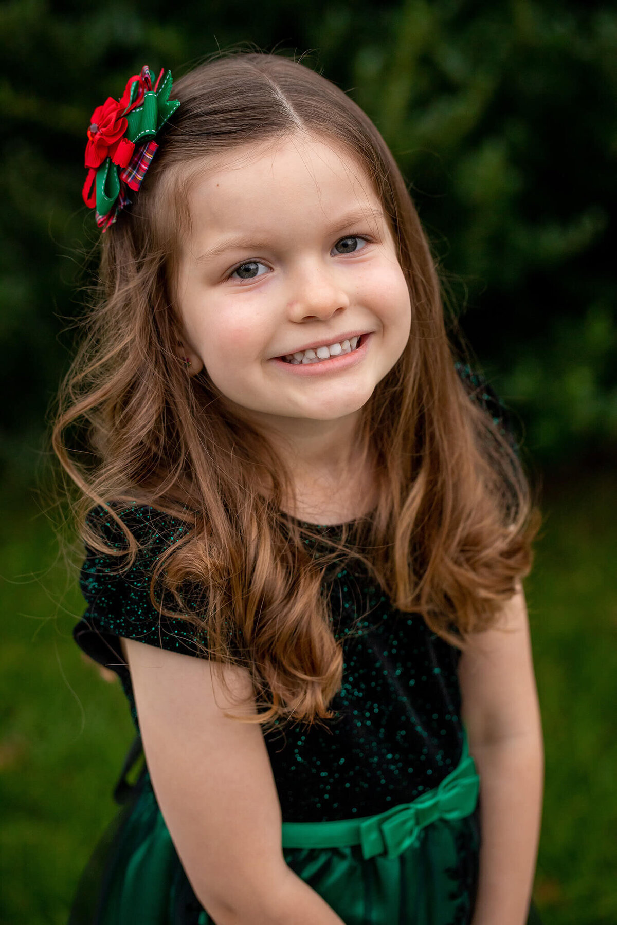 A Christmas picture of my daughter in a nice green dress and a Christmas bow in her hair.