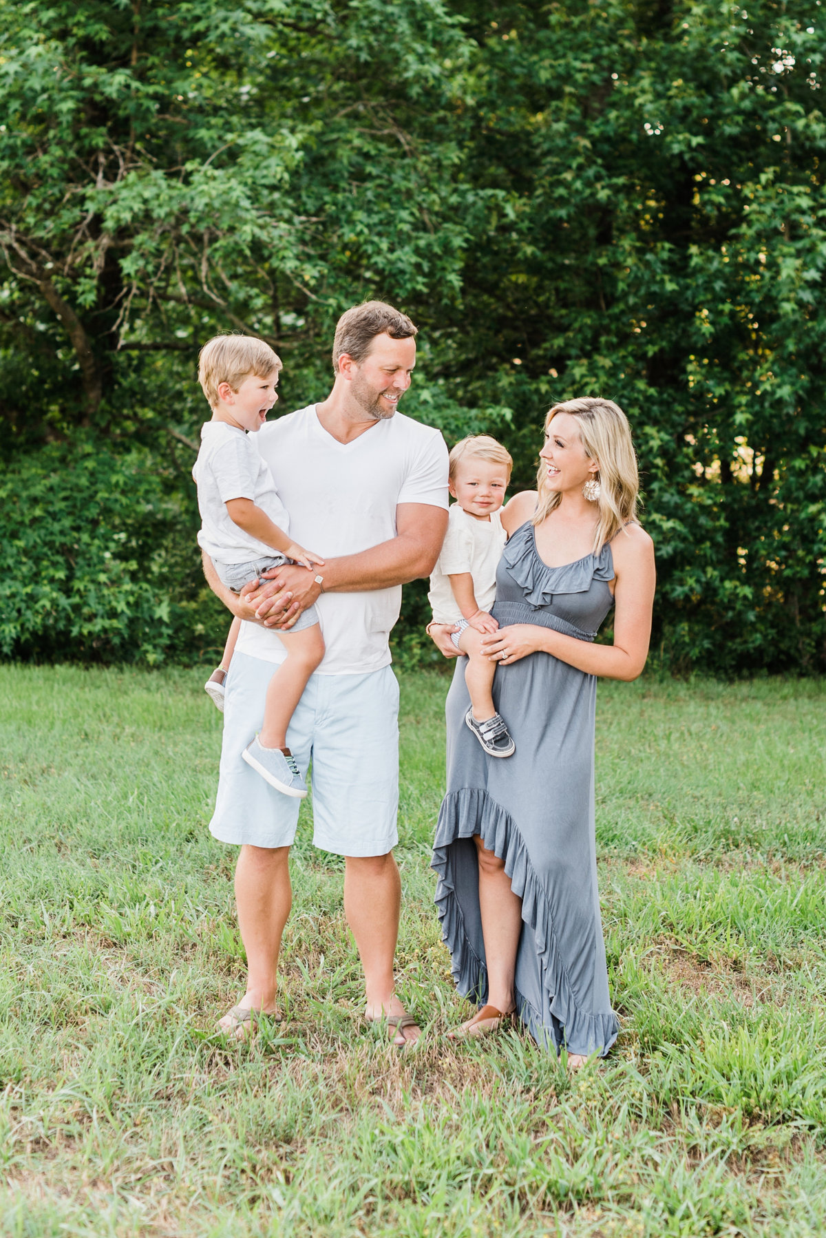 Family pauses for a photo together in a field during their Raleigh family photo session. Photographed by Raleigh NC family photographer A.J. Dunlap Photography.