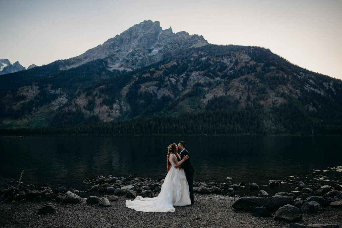 Eloped couple share kiss in front of mountian at Jenny Lake