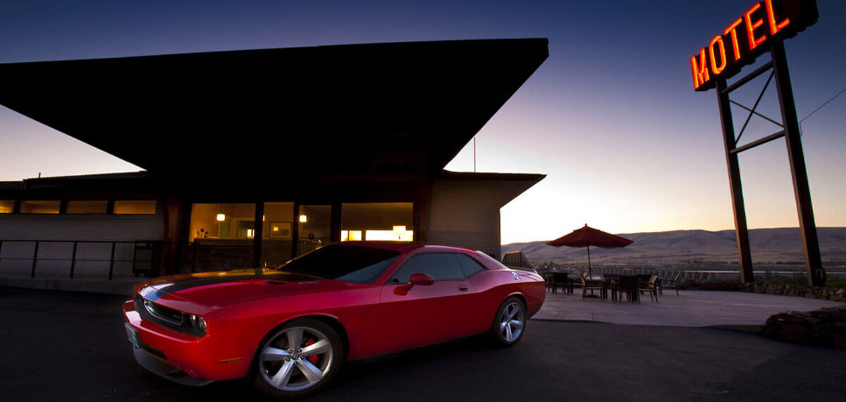 Red car in front of red motel sign at Celilo Inn