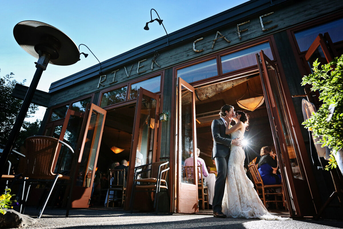 Couple kissing in the doorway of River Cafe, a riverside wedding venue in downtown Calgary, featured on the Brontë Bride Vendor Guide.
