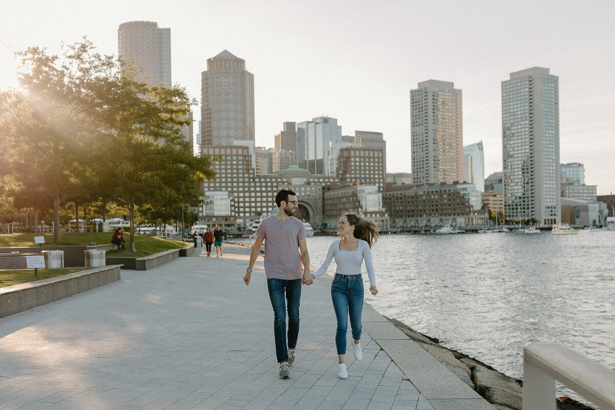 engaged couple running in seaport boston
