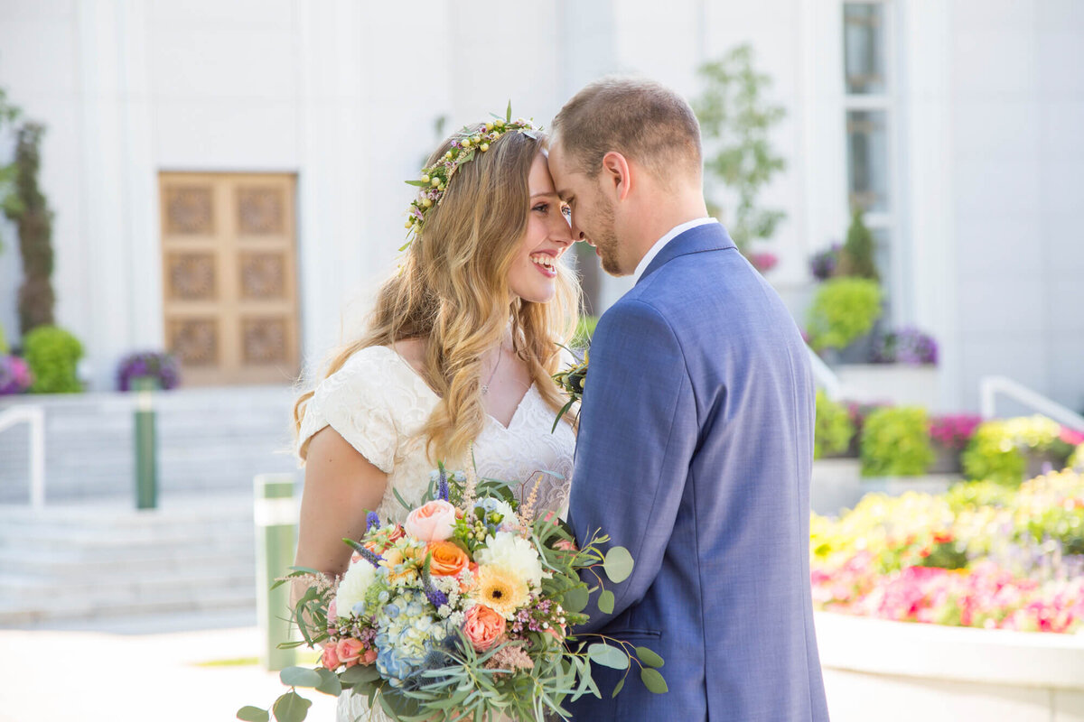 happy bride looks at groom with foreheads together at bright and joyful wedding