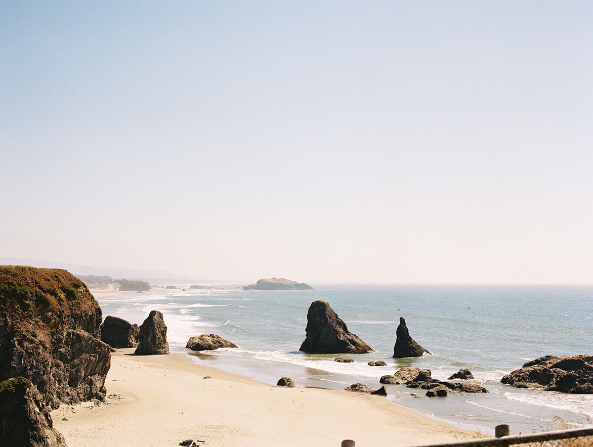 The ocean beach with rocks, representing the photography style of Among the Oaks. 