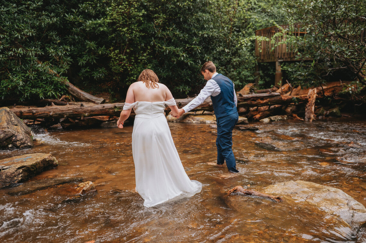 Two people hold hands and walk along a river