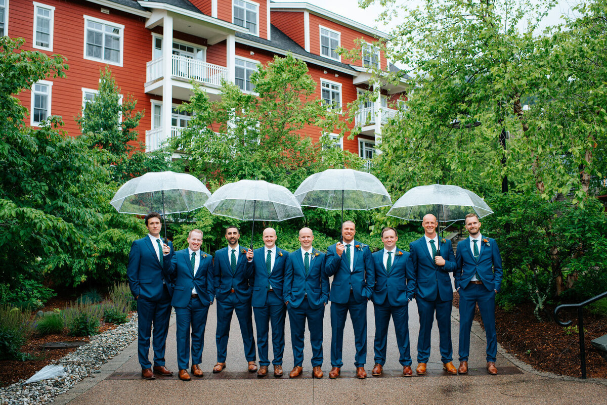 groomsmen in blue suits holding umbrellas at sugarbush resort vermont wedding