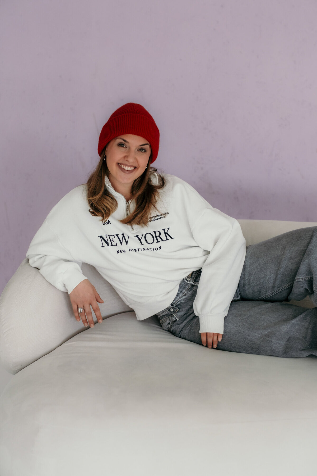 A woman lies smiling on a sofa.