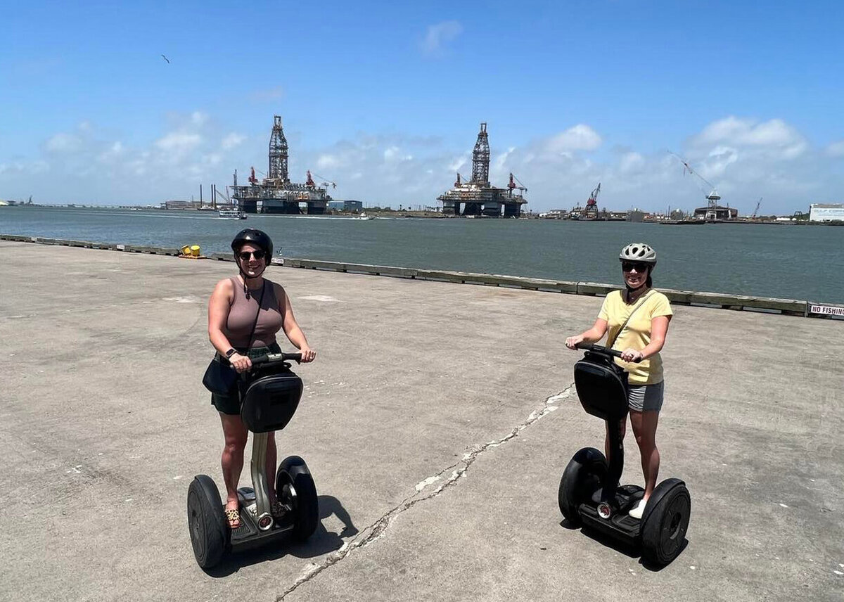 two women standing on Segway's in front of water in texas