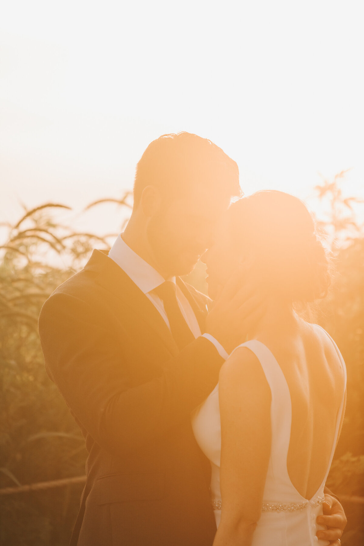 A bride and groom walking hand in hand at sunset on their Summer wedding day