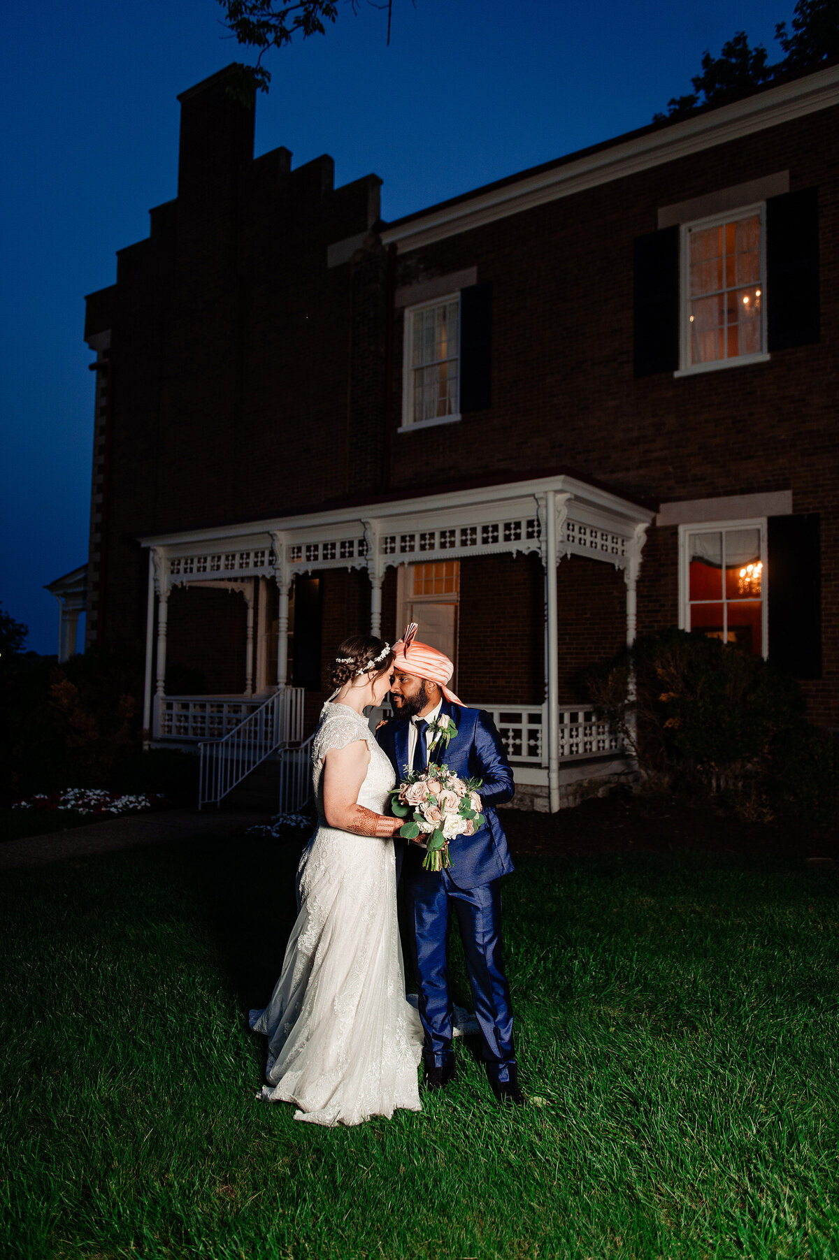 Newlyweds standing outside of Ravenswood Mansion at dusk on their wedding day
