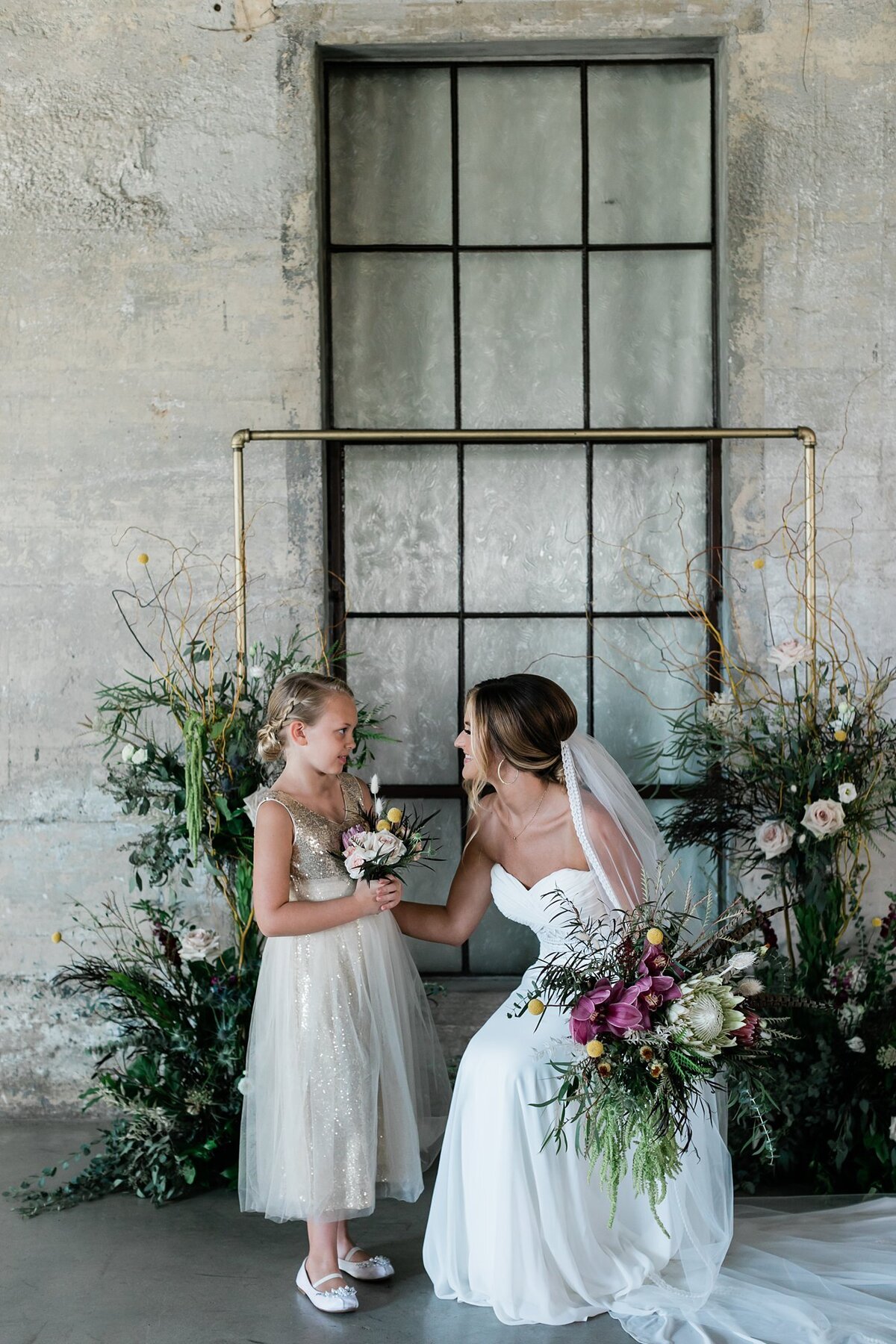 Bride crouching down to talk to the flower girl at her wedding at Olde Dobbin Station.