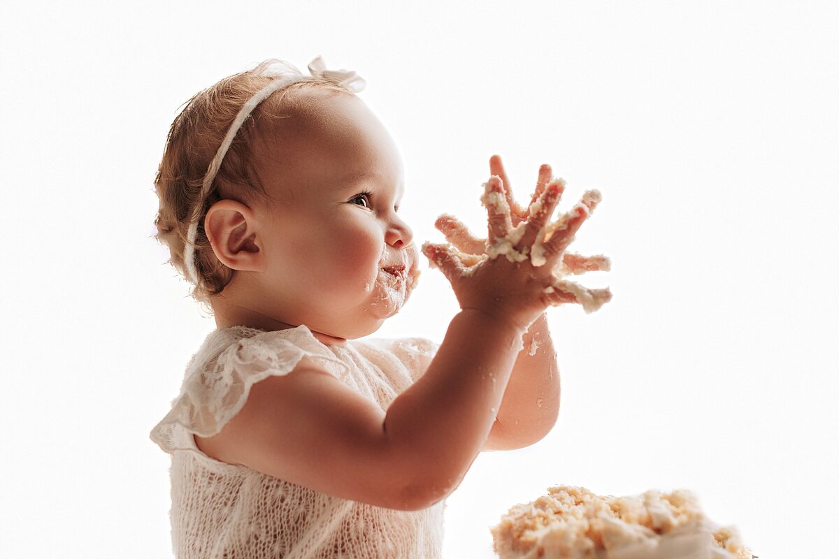 Baby smashing cake during first birthday session at Austin photo studio