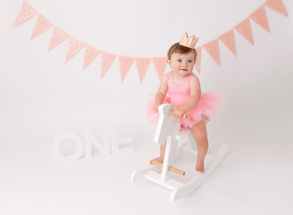 Baby girl at her first Birthday session sitting on the white horse  with pink tutu dress Brooklyn NY