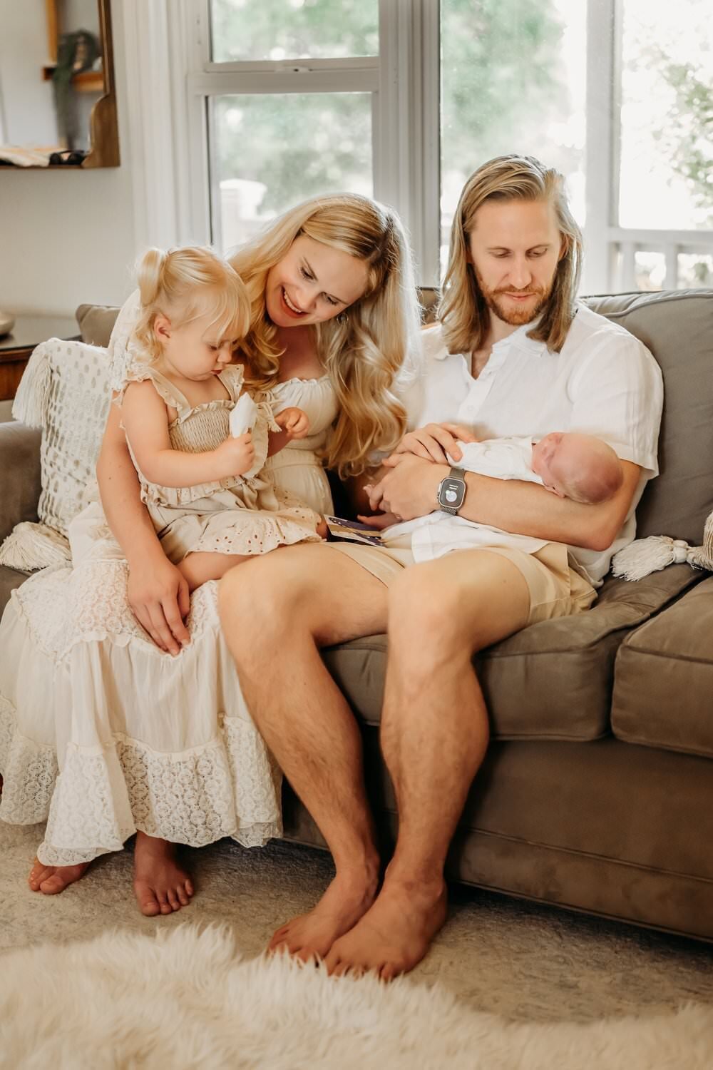 family on couch in their lafayette home cuddled together with their newborn baby