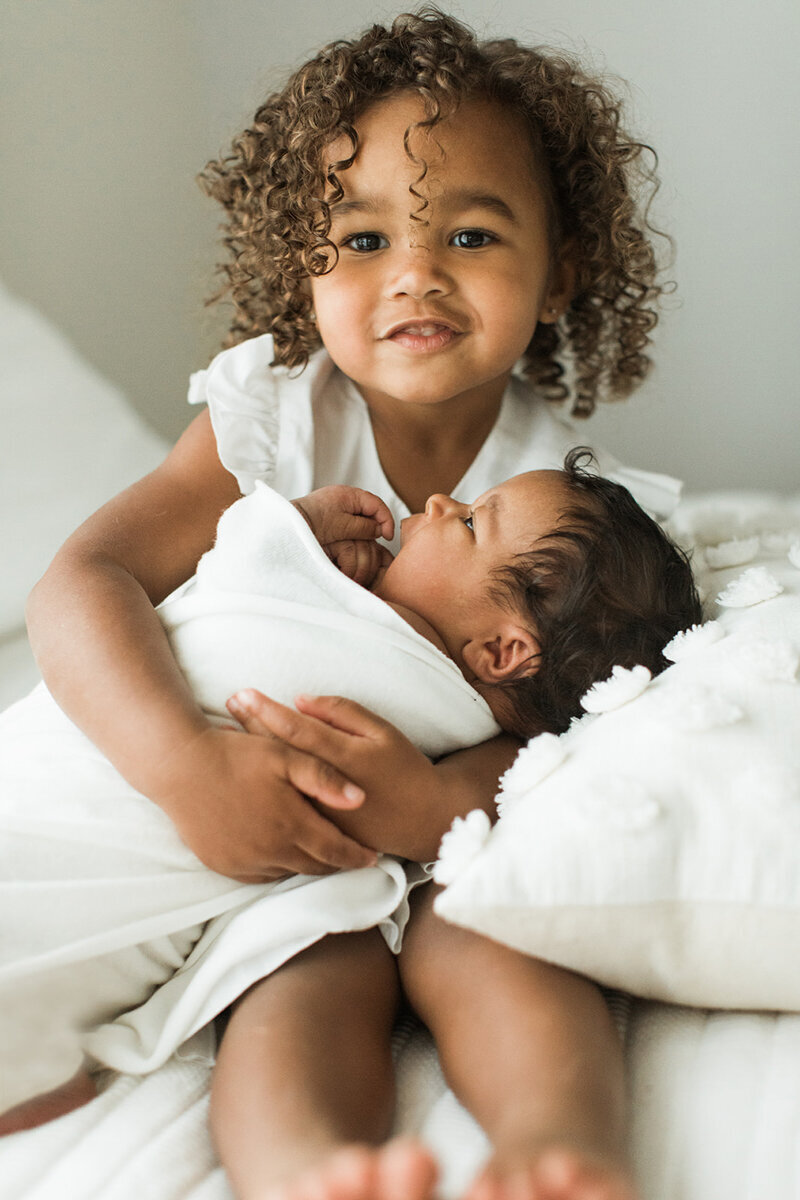 big sister proudly holds her new baby sister