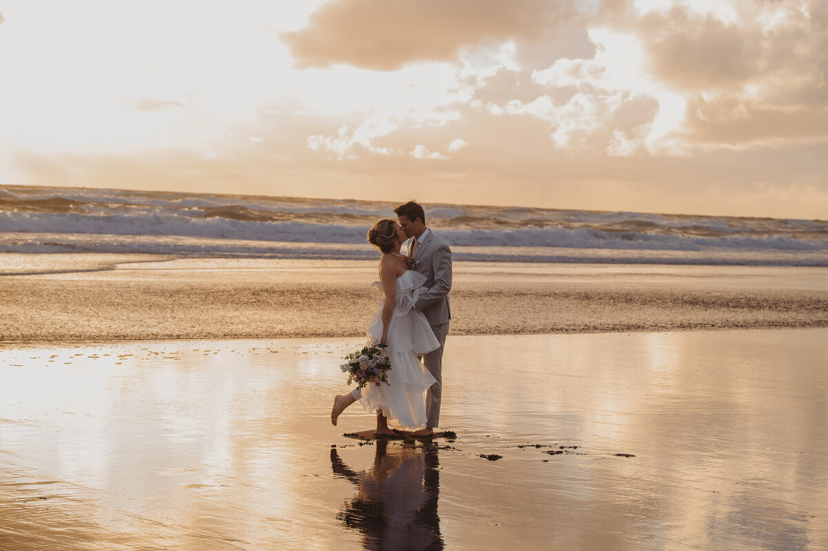 Photo of newly married couple on beach kissing