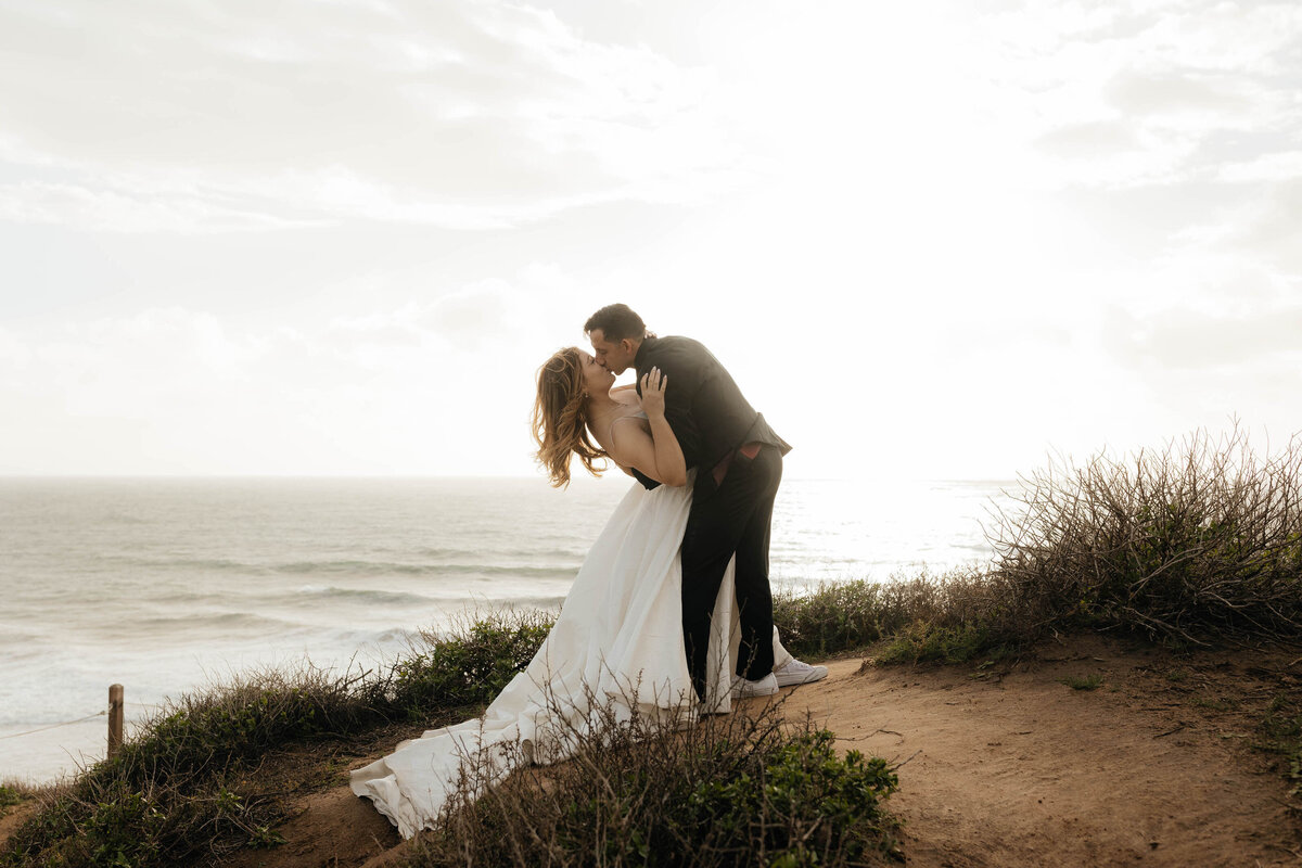 Groom dips the bride to kiss her during their bridal session at Newport Beach California