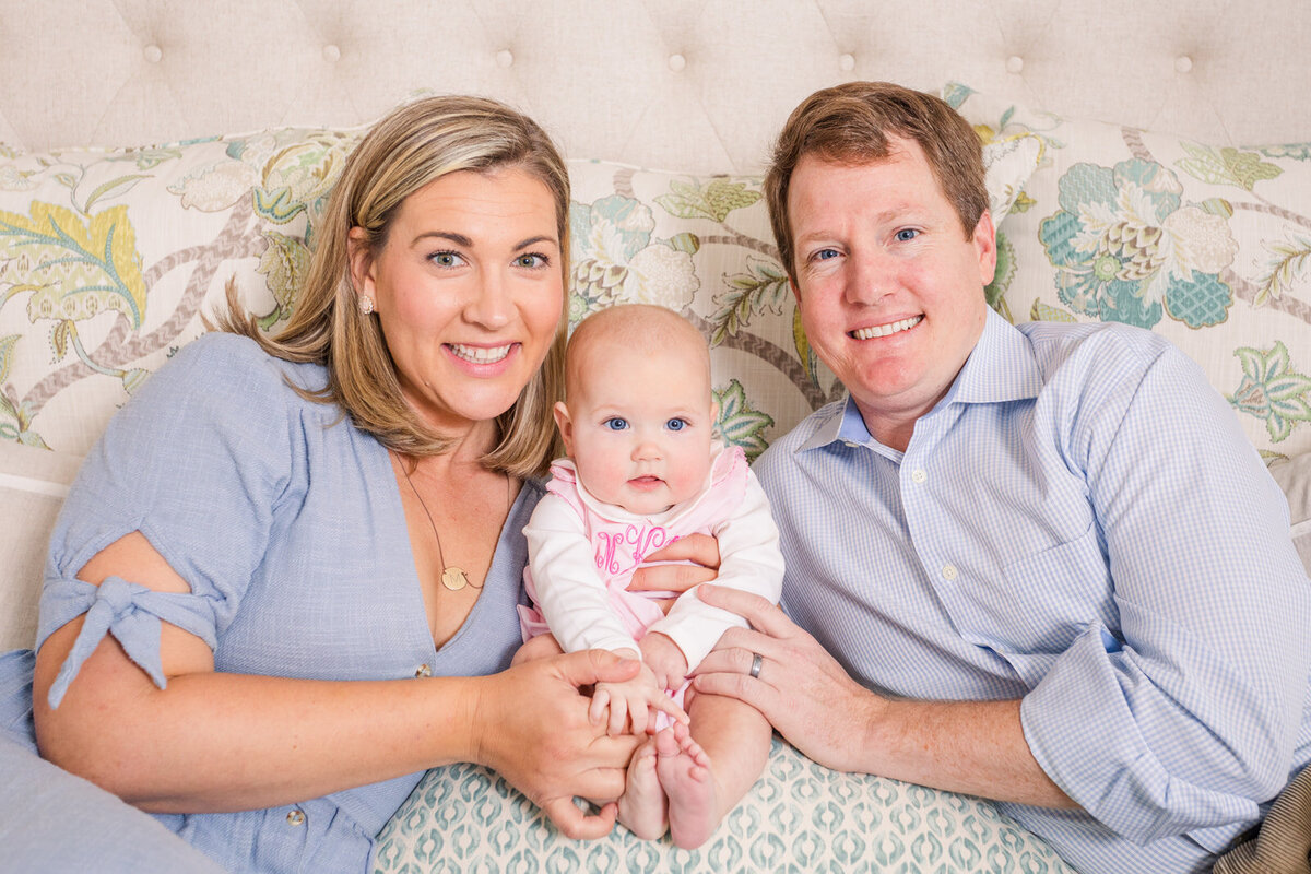 parents in blue with newborn baby sitting on parent bed