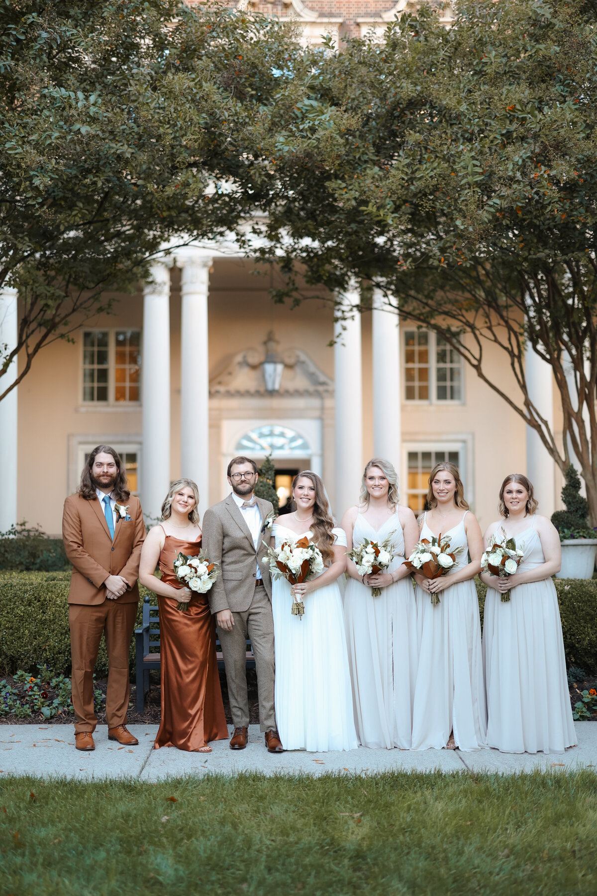 Wedding party standing in front of a natural green backdrop.