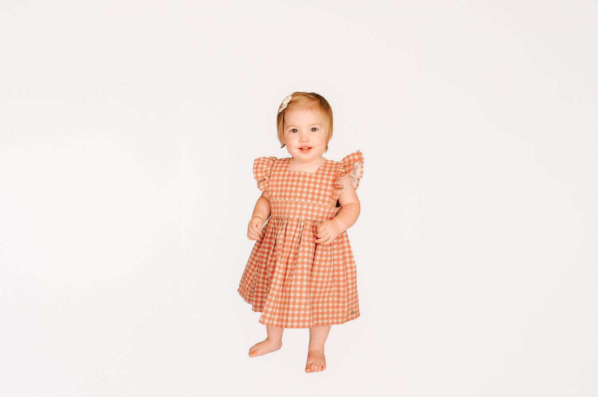 1st birthday milestone photography session of 1 year old girl walking in kids photography studio in Springfield mo