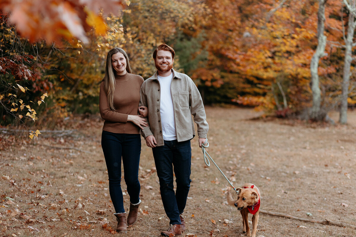 Couple taking photos for their anniversary. At Bradbury state park in Maine during fall/autumn with their dog.