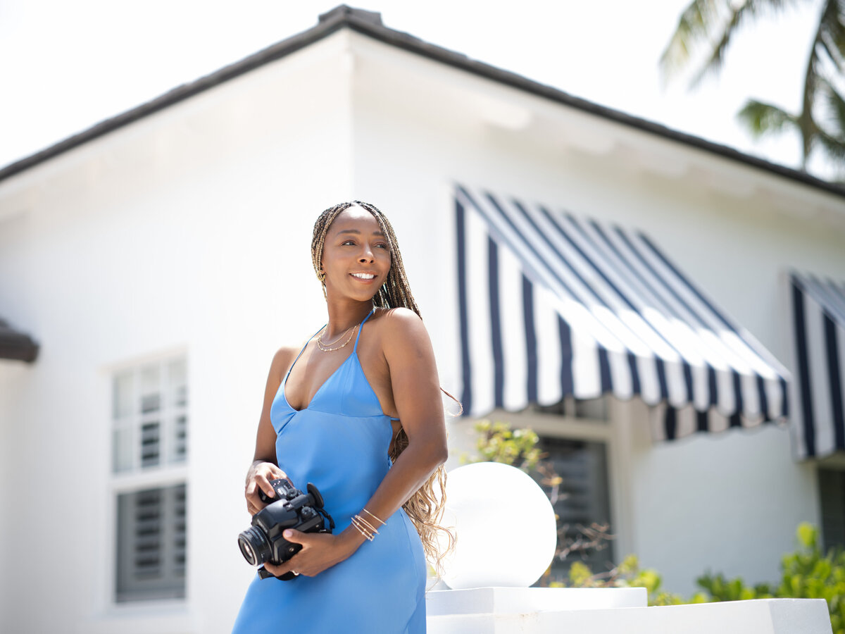 Black female photographer holding a Pentax film camera at The Potlatch Club in Eleuthera
