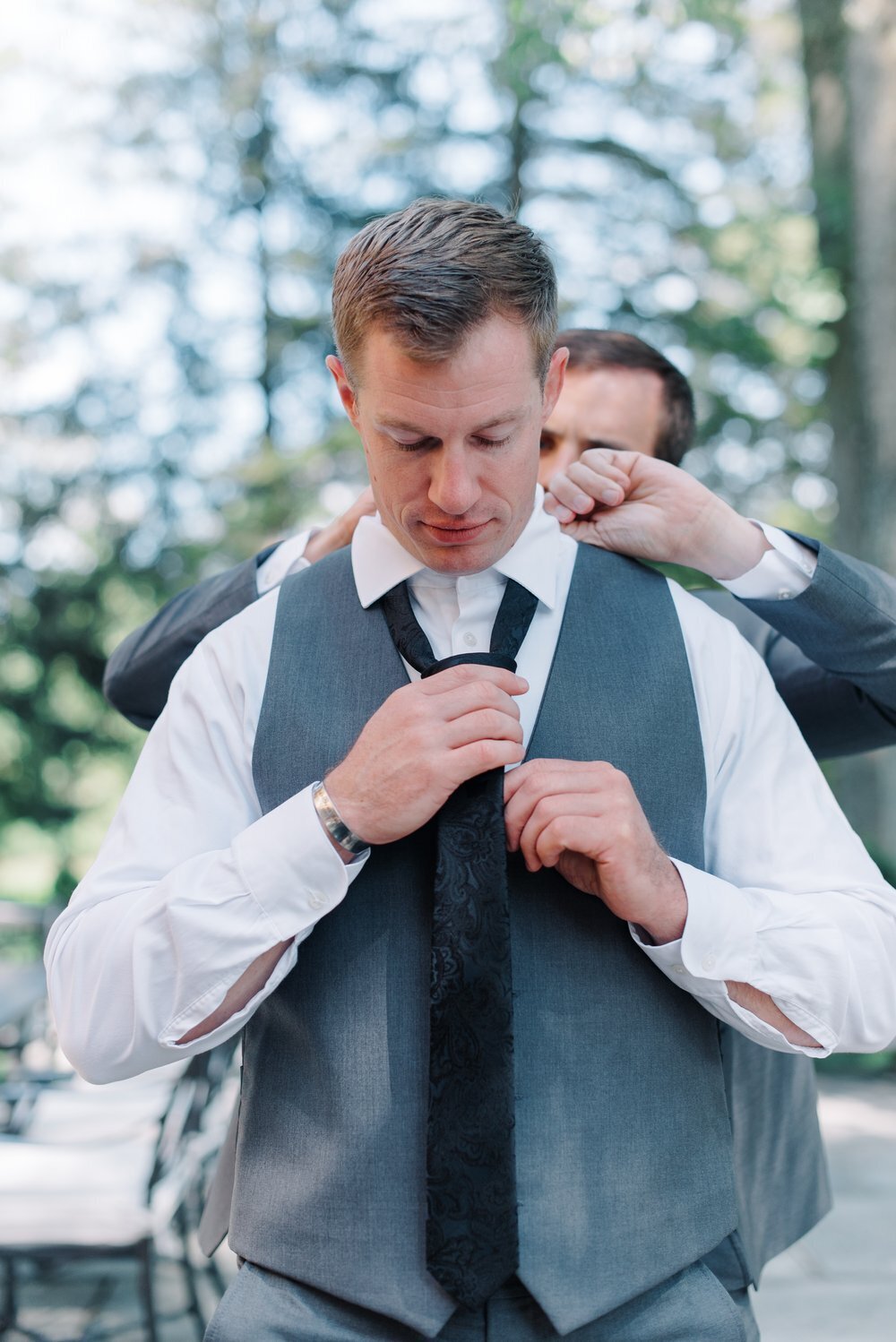 Groomsman helps groom get ready for wedding