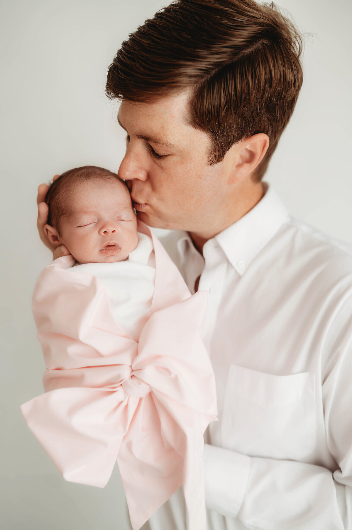 Father kisses his infant during Newborn Portrait Session in Asheville.