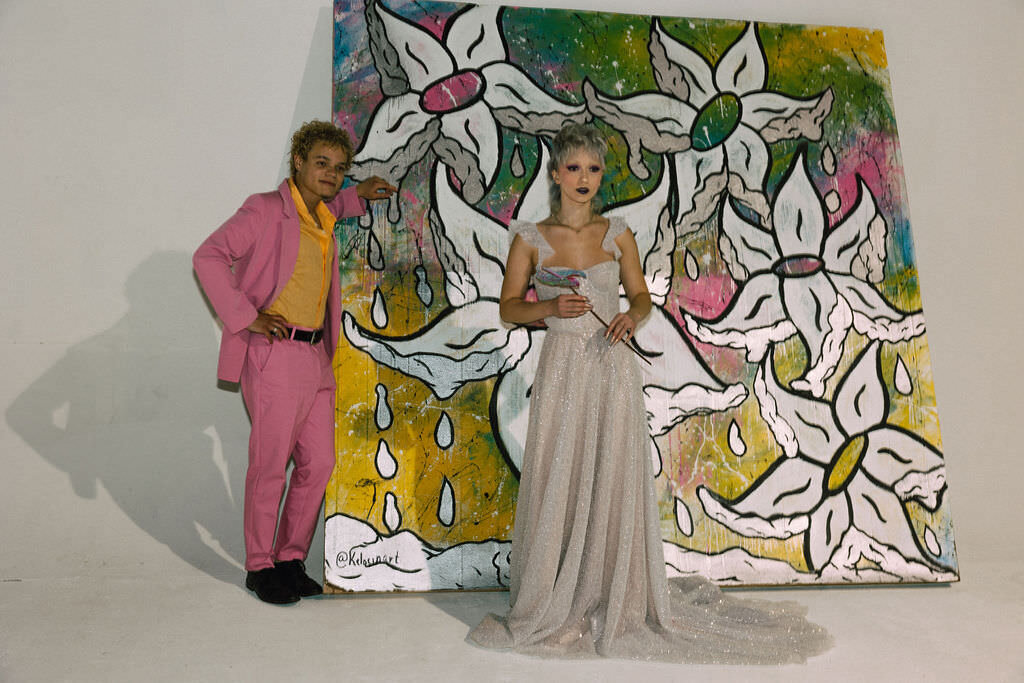 A wedding couples standing in front of a colorful mural.