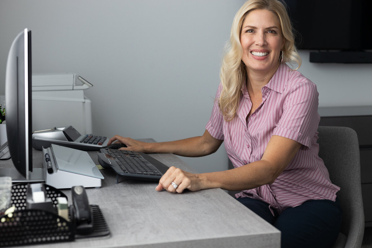 Bookkeeper smiling at camera sitting at desk