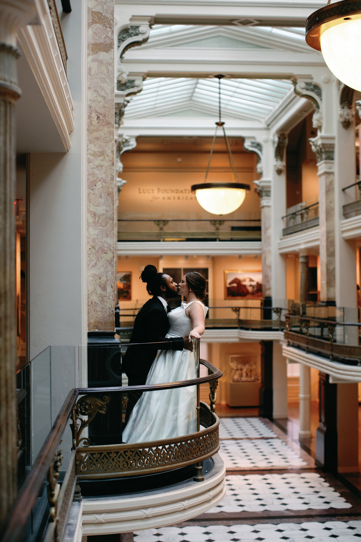 A bride and groom share a kiss inside the National Portrait Gallery after their upscale classy DC wedding.