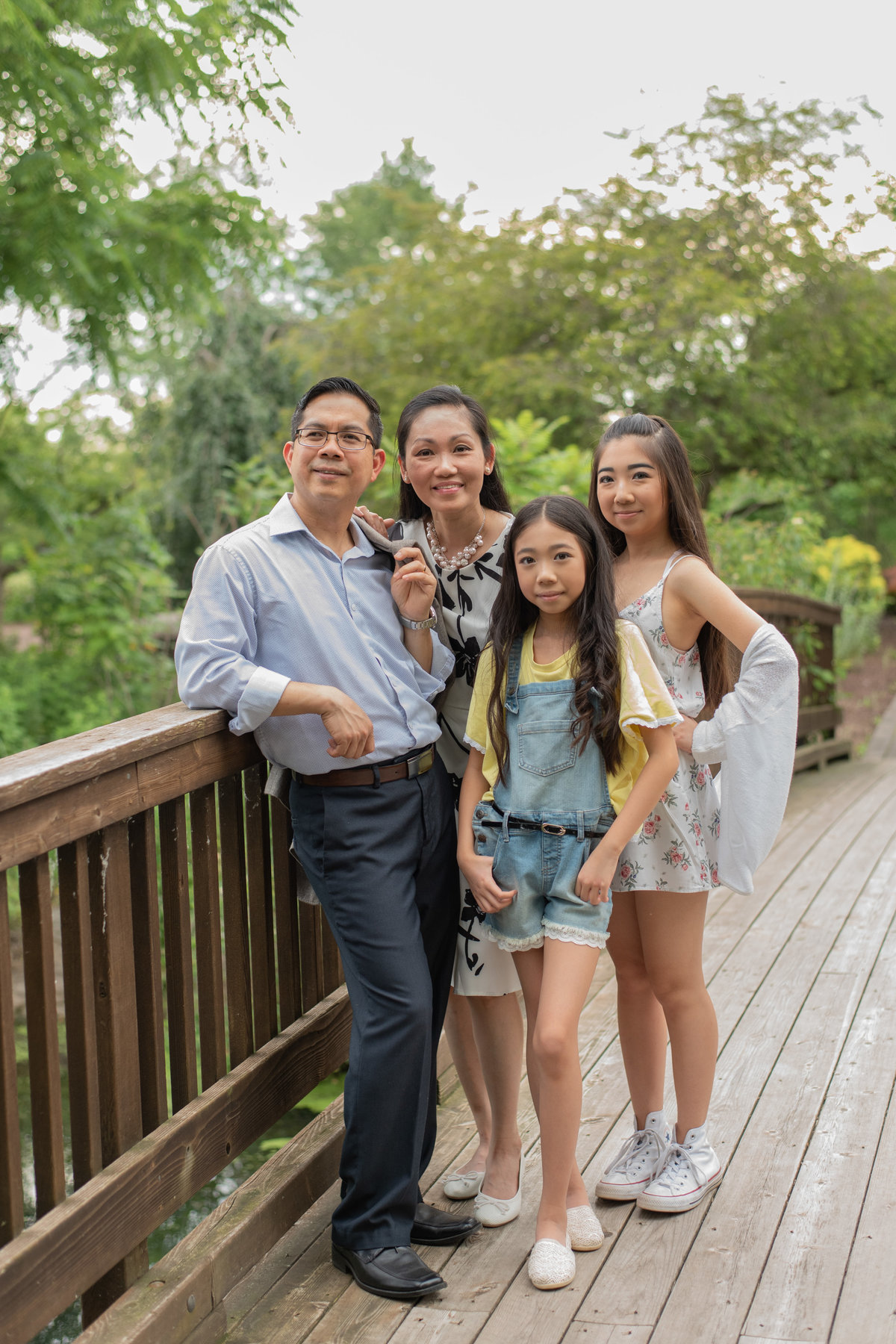 Family of 4 standing together on wooden bridge