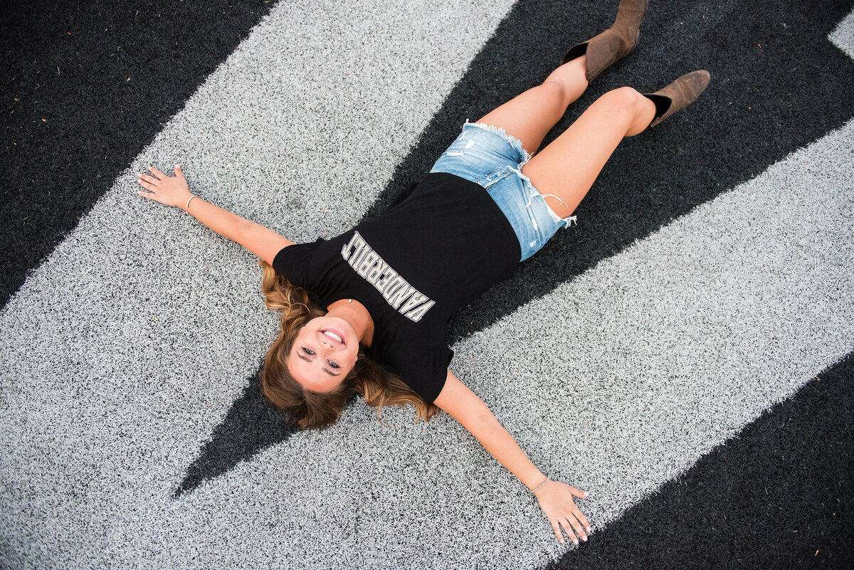 Senior girl laying on the Vanderbilt football field