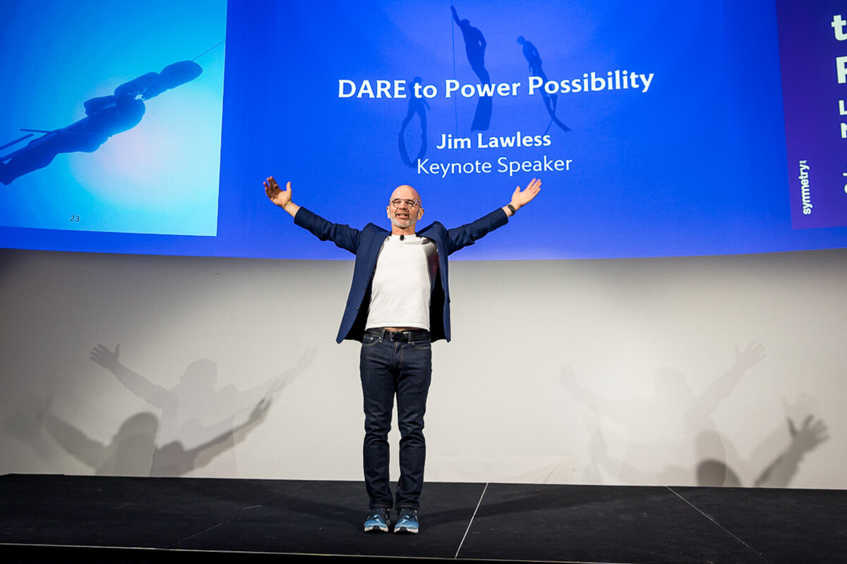 Professional headshot style of keynote speaker in blazer presenting passionately on stage with screen background new jersey.