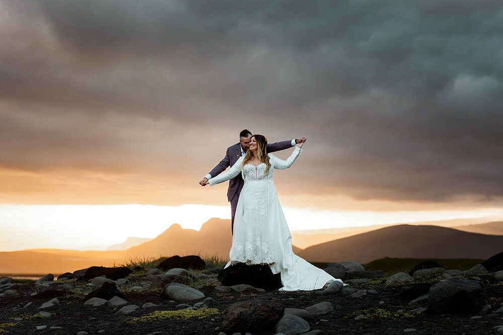 Married couple is having fun on the black sand beach during sunset in Iceland