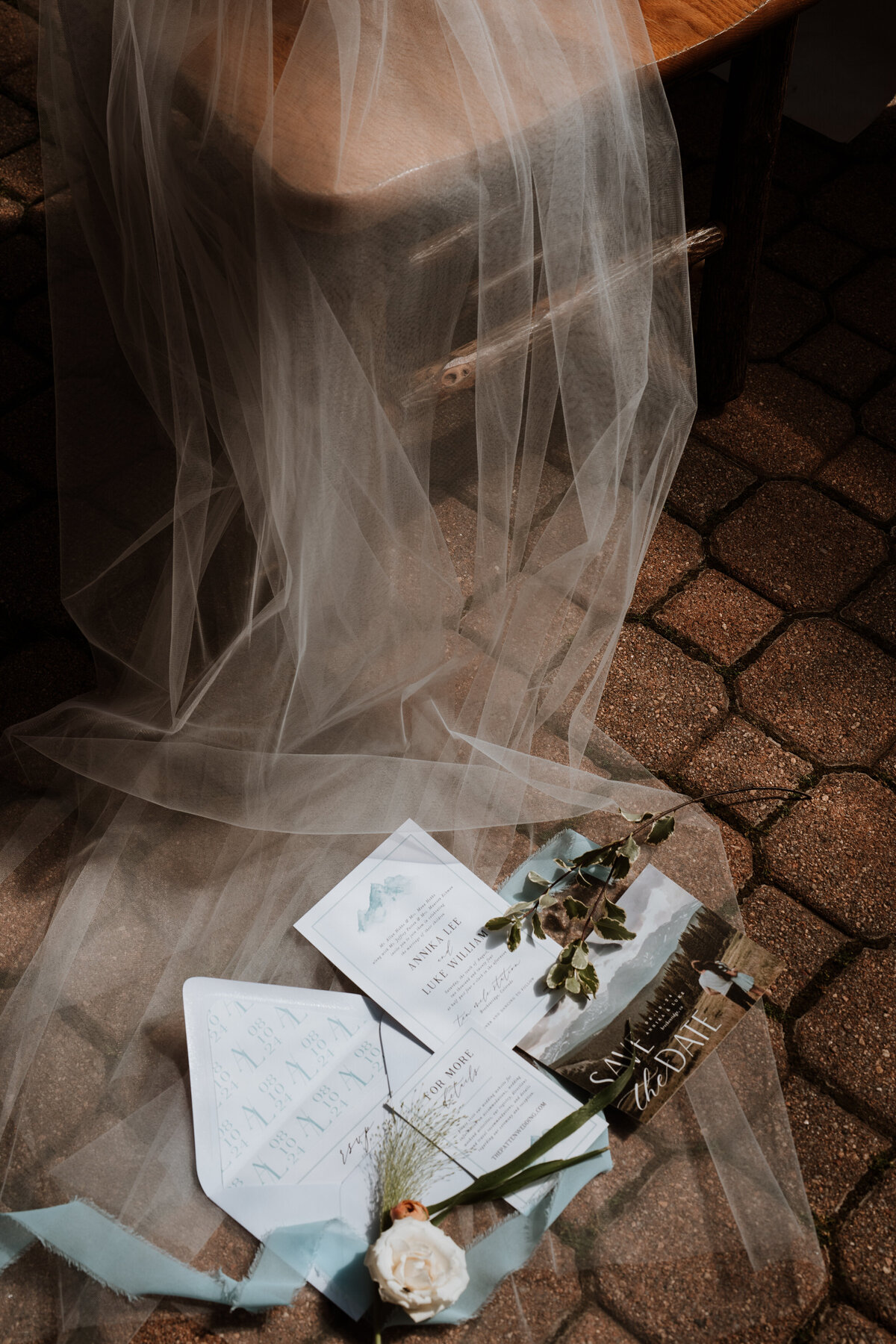 Flat lay of Ten Mile Station wedding stationery and veil on rustic stone patio with natural light.
