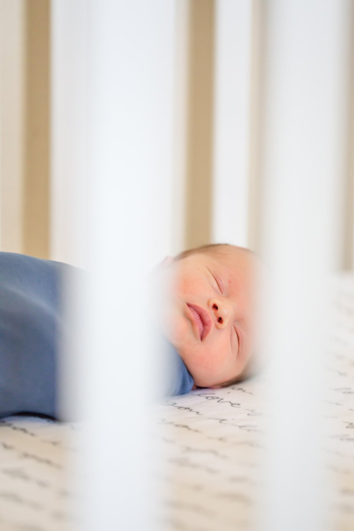 Sleepy newborn in his crib at a lifestyle newborn session with Erin Thompson Photography