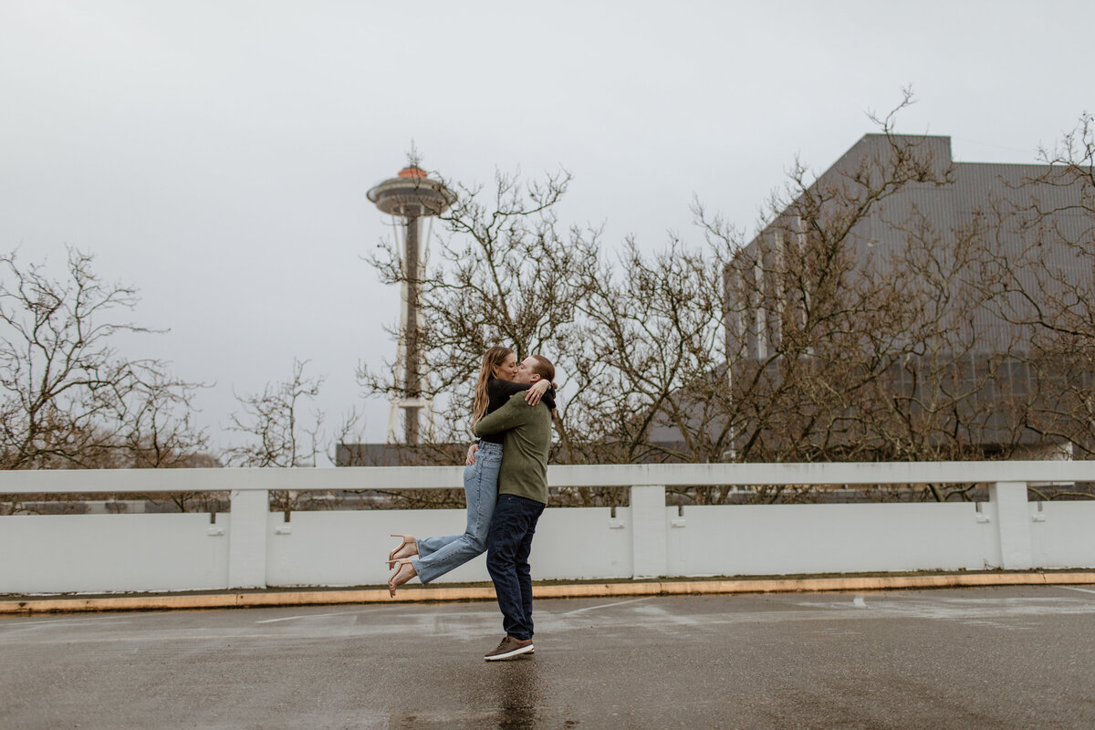 A rainy rooftop parking garage engagement session in Seattle with the Space Needle in the background. Captured by Fort Worth Wedding Photographer, Megan Christine Studio