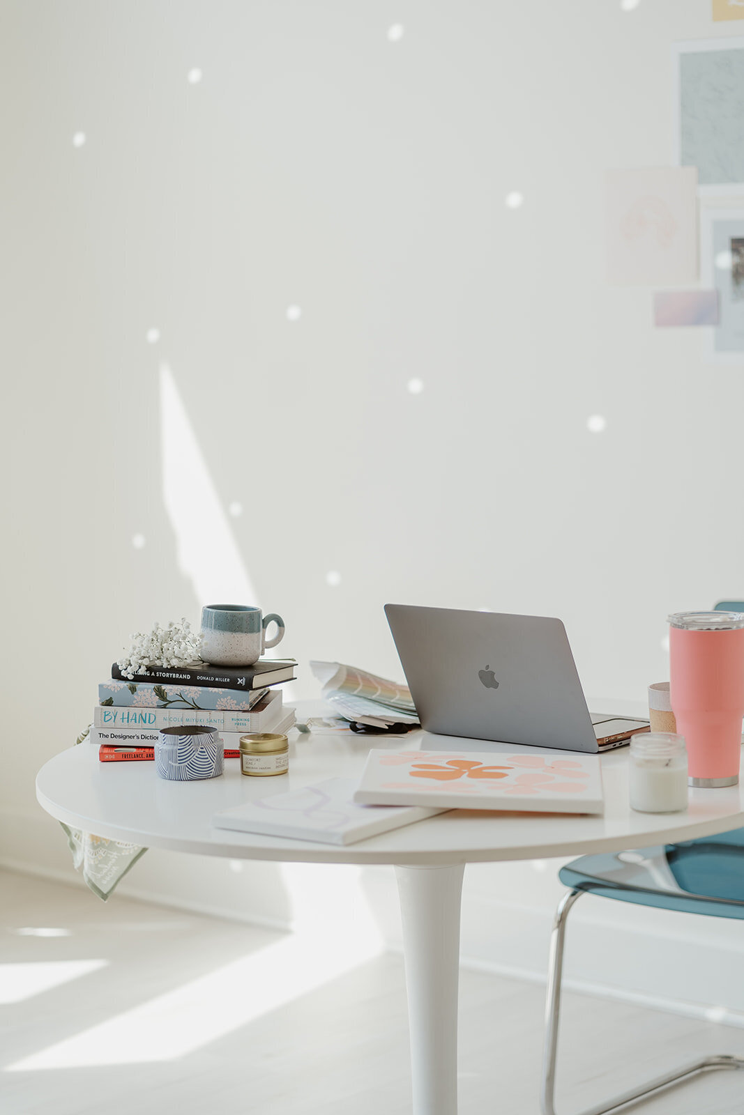 Close-up photo of a white table with a laptop, coffee, and creative materials during a Wildher and Co branding session.