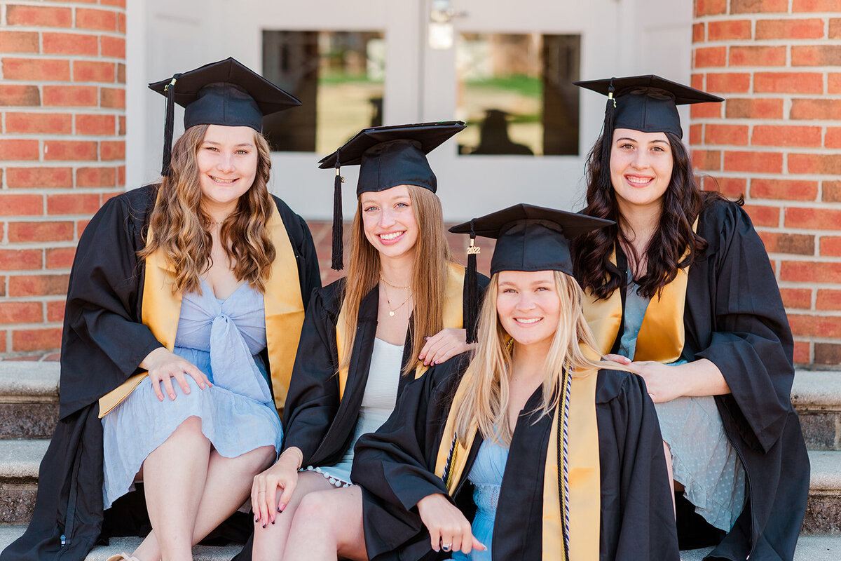 College graduation portraits beneath cherry blossoms