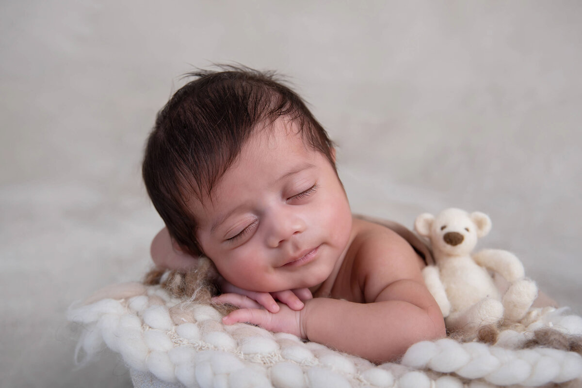 up close photo of a newborn boy in a bowl on a beige background for his newborn photography session