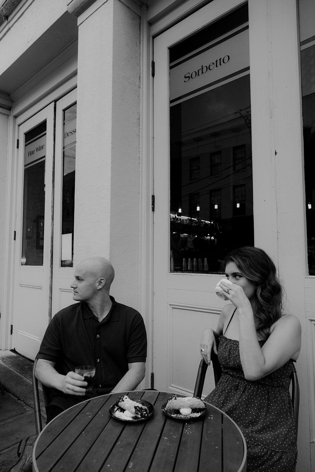 Couple sitting outside of cafe with coffee making engagement session a coffee date